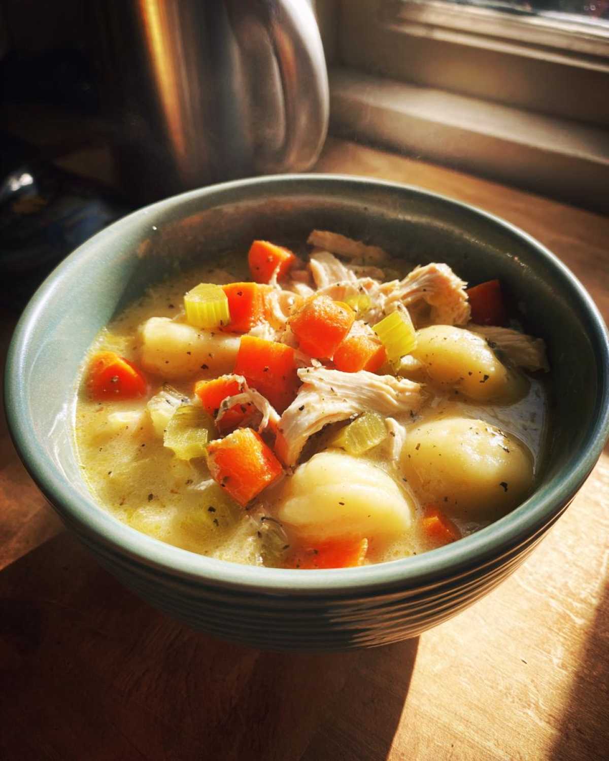 A close-up bowl of creamy Olive Garden Chicken Gnocchi Soup with shredded chicken, carrots, celery, and gnocchi.