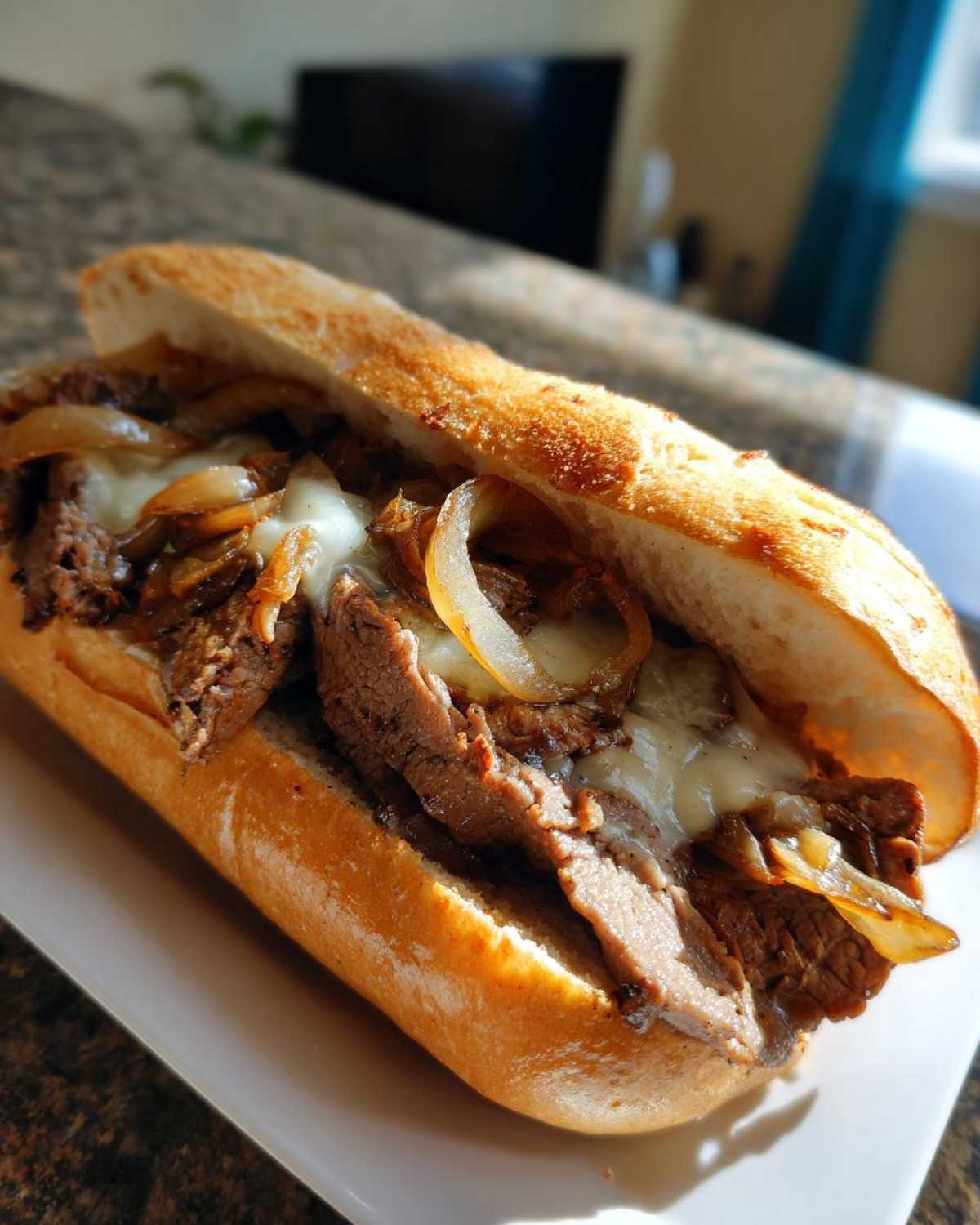 Close-up of a mouthwatering Philly cheesesteak sandwich filled with thinly sliced steak, melted cheese, and caramelized onions on a toasted roll.
