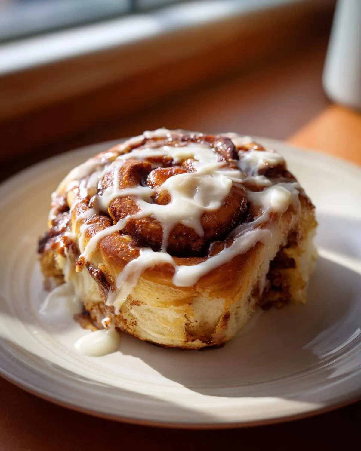 A close-up of a delicious Pistachio Cream Cinnamon Roll drizzled with white icing.