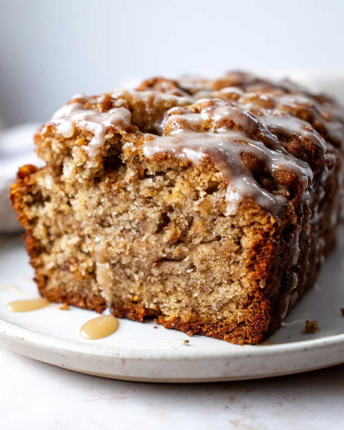 Close-up of a slice of moist pumpkin banana bread topped with a sweet glaze.