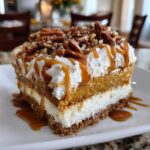 A decadent slice of Pumpkin Cheesecake Lasagna topped with whipped cream, caramel drizzle, and pecans.