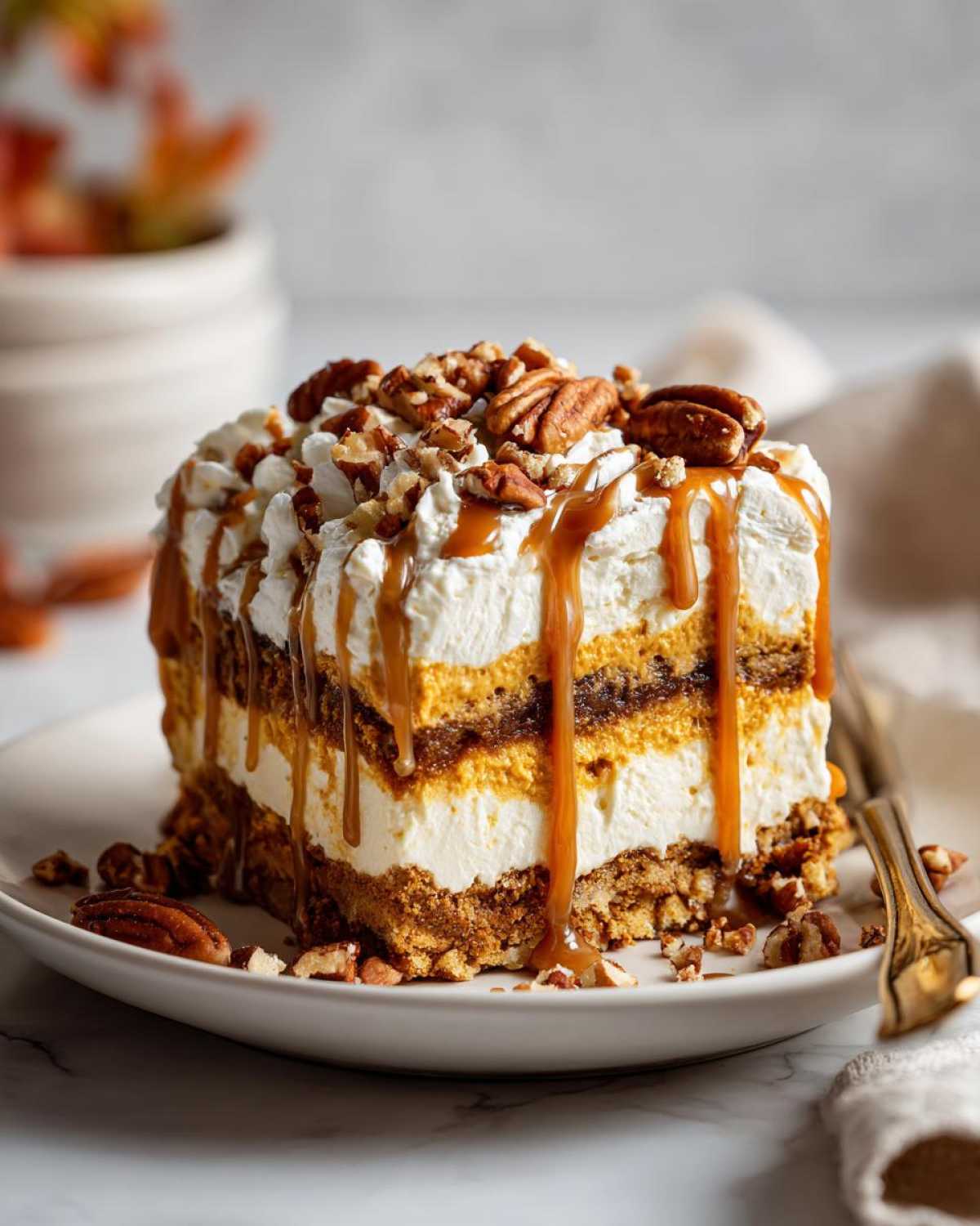 A decadent slice of Pumpkin Cheesecake Lasagna topped with whipped cream, caramel drizzle, and chopped pecans.
