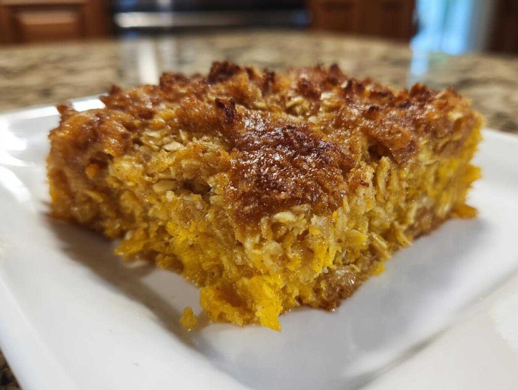 A close-up shot of a golden-brown slice of Pumpkin Oatmeal Dump Cake on a white plate.