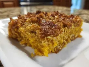 A close-up shot of a golden-brown slice of Pumpkin Oatmeal Dump Cake on a white plate.