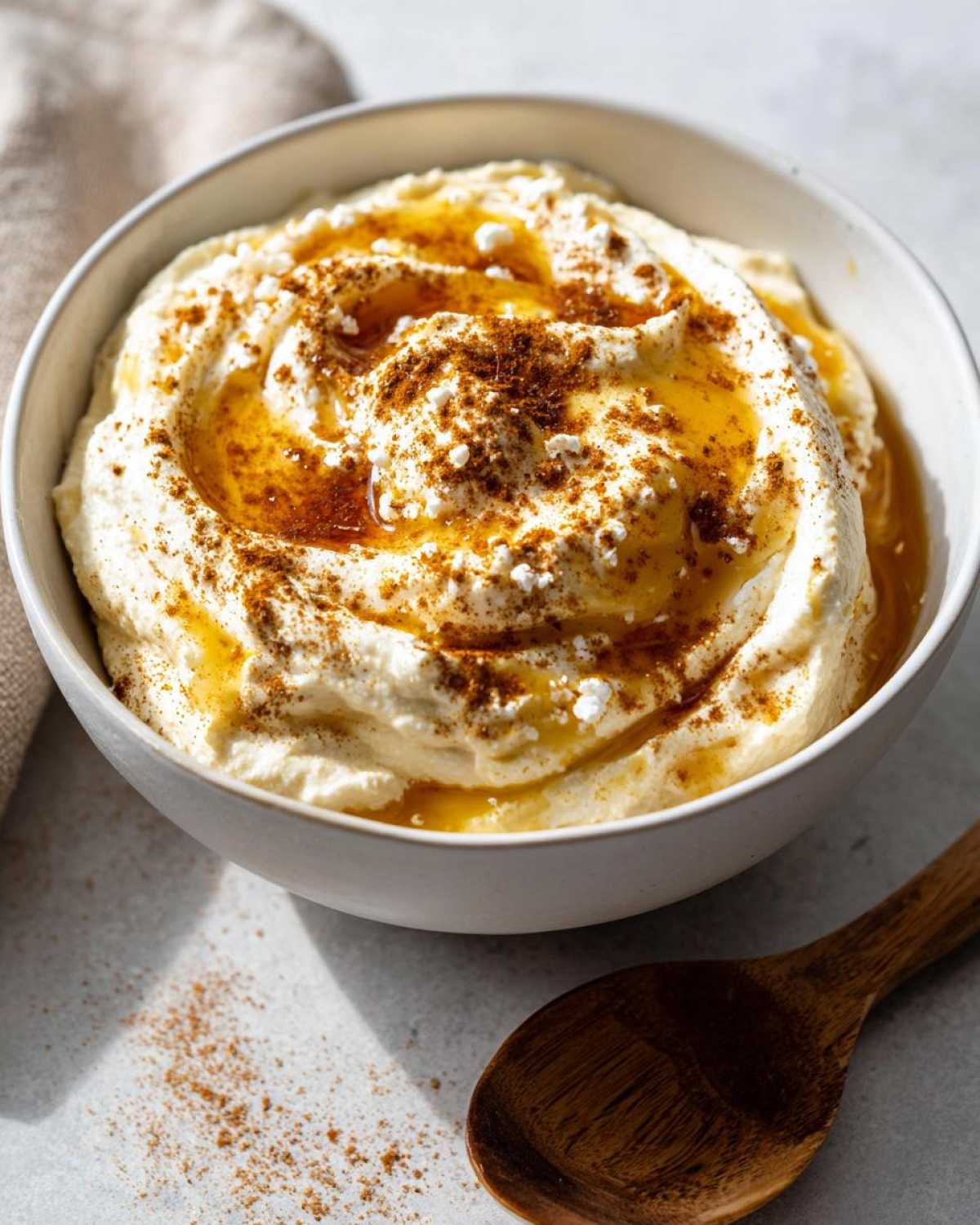 Close-up of a bowl filled with creamy pumpkin whipped feta honey dip, drizzled with honey and sprinkled with cinnamon.