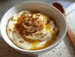 A bowl of creamy Pumpkin Whipped Feta Honey Dip drizzled with honey and sprinkled with cinnamon.