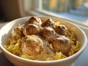 A bowl of delicious slow cooker Swedish meatballs served over egg noodles and covered in creamy sauce.
