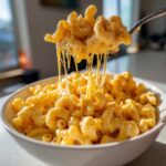 A fork lifting a cheesy portion of creamy stovetop mac and cheese, showcasing a satisfying cheese pull.