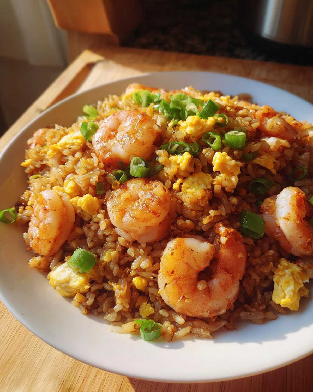 Close-up of delicious shrimp fried rice topped with large seasoned shrimp, scrambled egg, and green onions.
