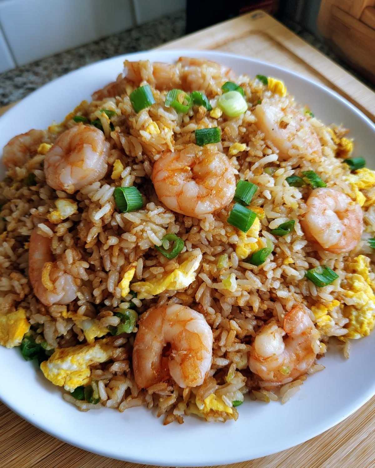 Close-up of flavorful shrimp fried rice mixed with scrambled eggs and topped with green onions.