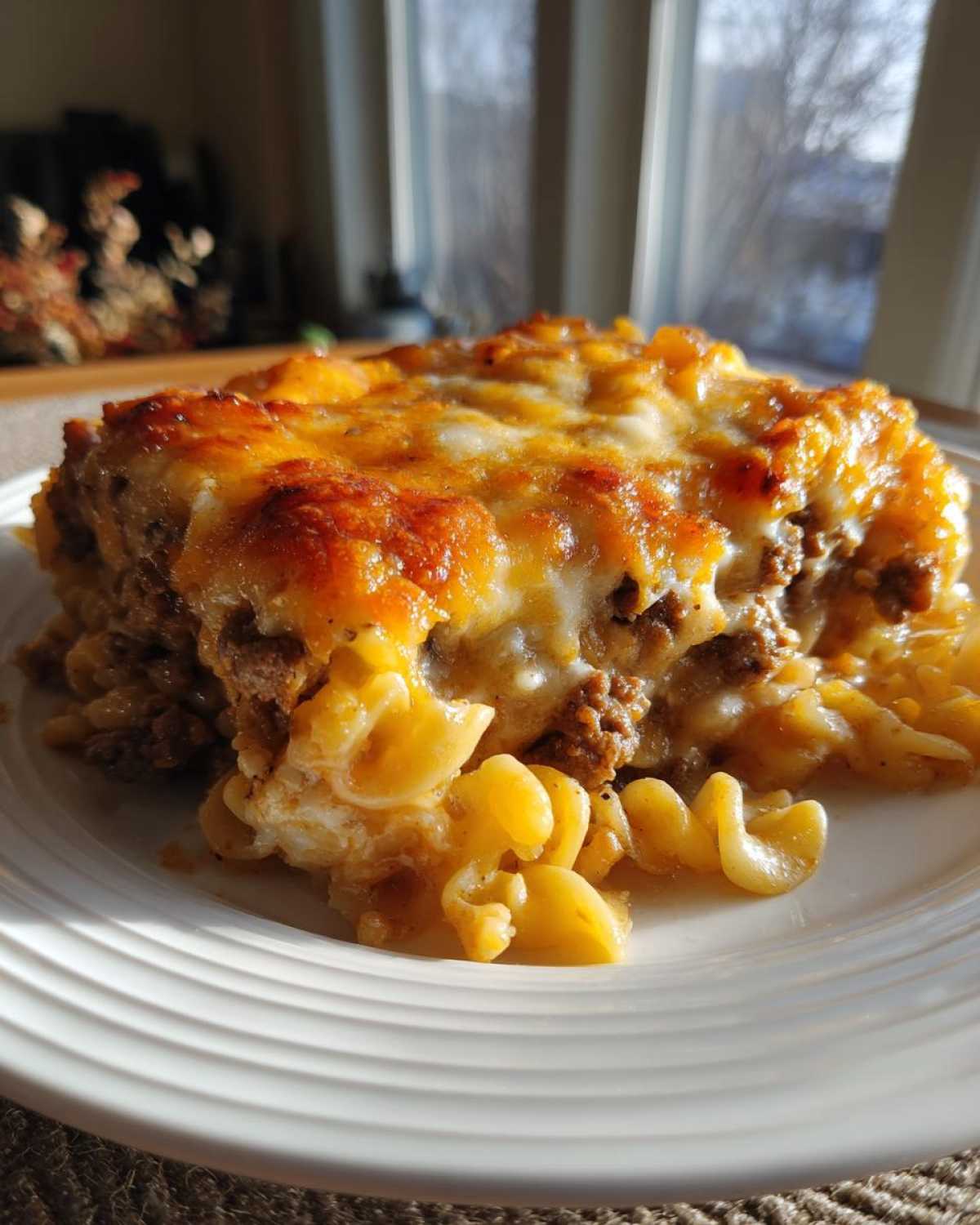 A close-up of a hearty Amish Country Casserole slice with pasta, ground meat, and melted cheese.
