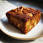 A slice of chewy apple brownies topped with walnuts, showcasing chunks of apple within.