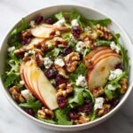 A refreshing apple feta salad with arugula, sliced apples, walnuts, dried cranberries, and crumbled feta cheese.