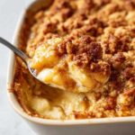 A spoonful of warm Apple Pie Dip with a golden crumble topping, showing creamy apple filling.