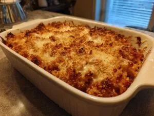 A golden brown baked chicken Parmesan casserole in a white baking dish, with a crispy breadcrumb topping.