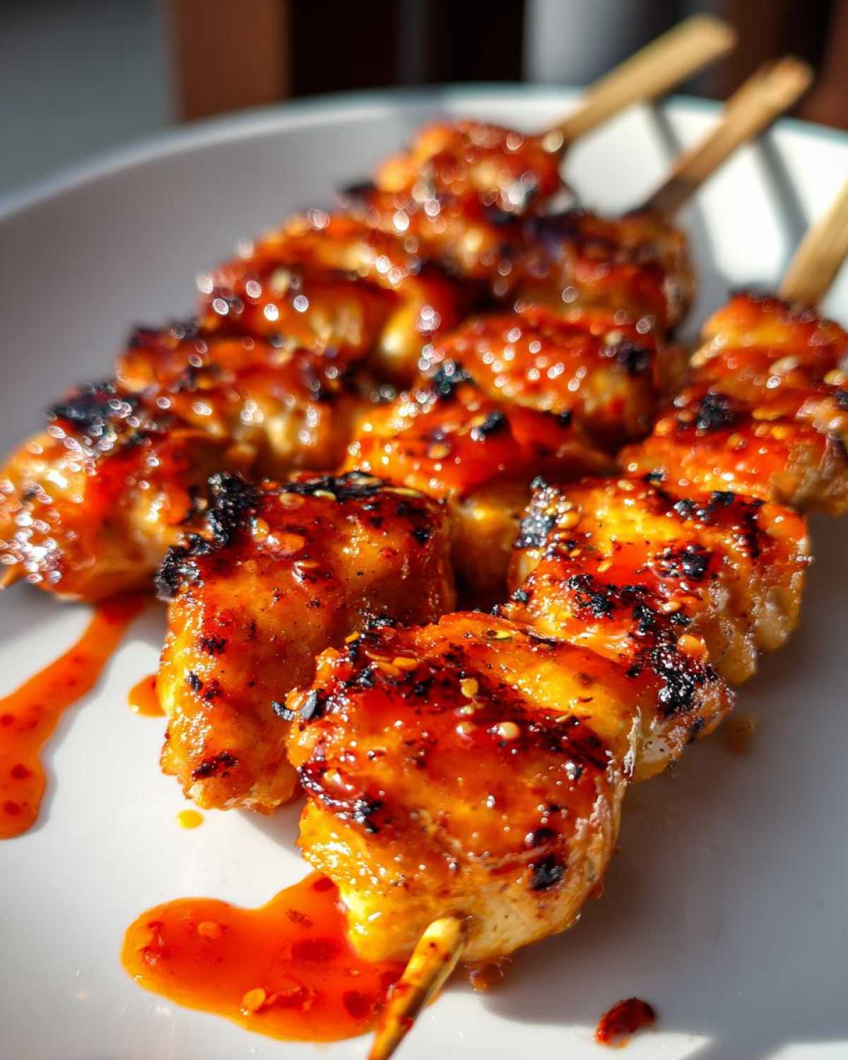 Close-up of delicious Bang Bang Chicken Skewers glazed with a spicy sauce and sprinkled with sesame seeds.