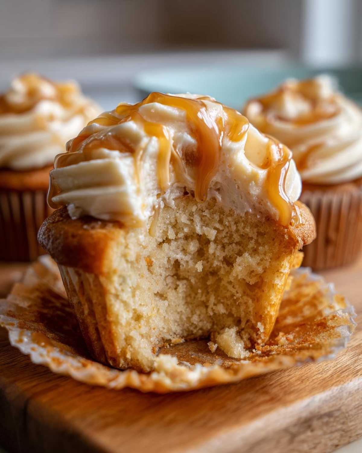 A bite taken out of a moist Butterbeer cupcake topped with creamy frosting and a rich caramel drizzle.