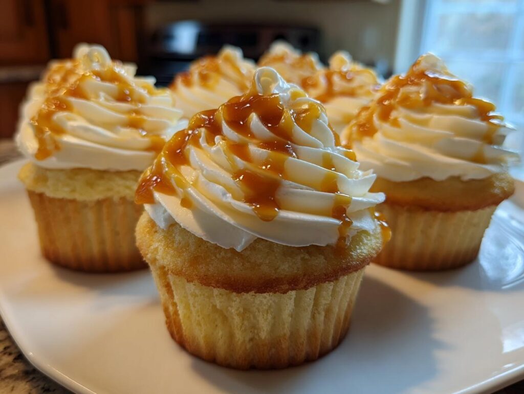 Close-up of fluffy Butterbeer cupcakes topped with white frosting and drizzled with caramel sauce.