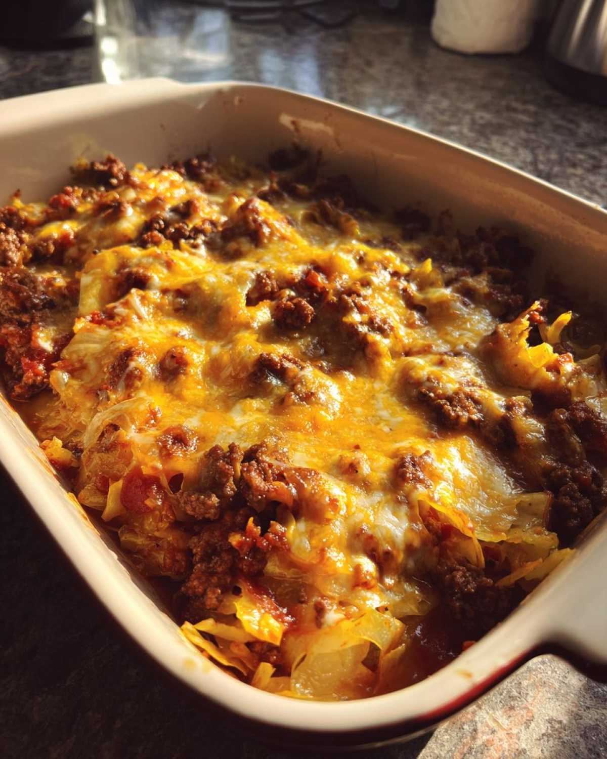 Close-up of a freshly baked cabbage beef bake in a casserole dish, topped with melted cheese and seasoned ground beef.