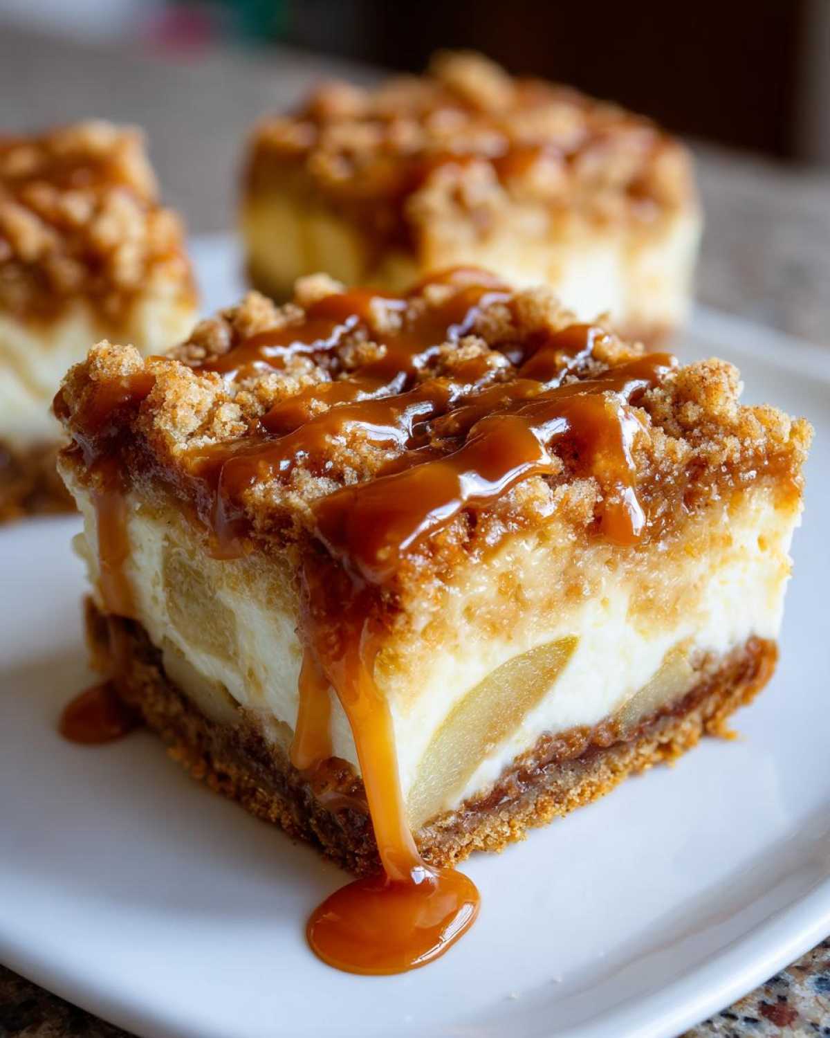 Close-up of a caramel apple cheesecake bar with a thick caramel drizzle and crumble topping.