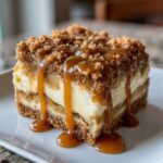 A decadent slice of caramel apple cheesecake bars topped with a crumbly streusel and drizzled with rich caramel sauce.