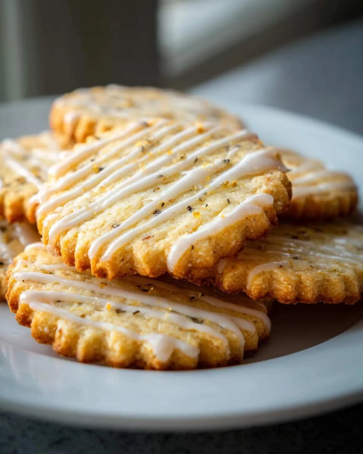 A stack of cardamom shortbread cookies drizzled with white glaze and flecks of spice.