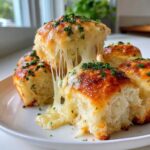 Close-up of ultra-soft cheesy garlic rolls, with melted cheese stretching between them and topped with fresh parsley.