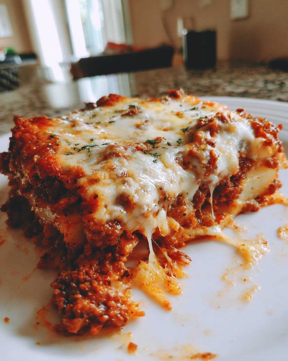 A delicious slice of cheesy ground beef and potato casserole, with melted cheese oozing out.