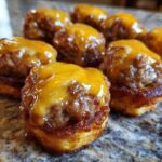 Close-up of several homemade mcgriddle bites topped with melted orange cheese, resting on a granite surface.