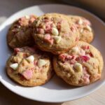A stack of soft, golden-brown cherry chip cookies with visible white chocolate chips and pink cherry pieces.
