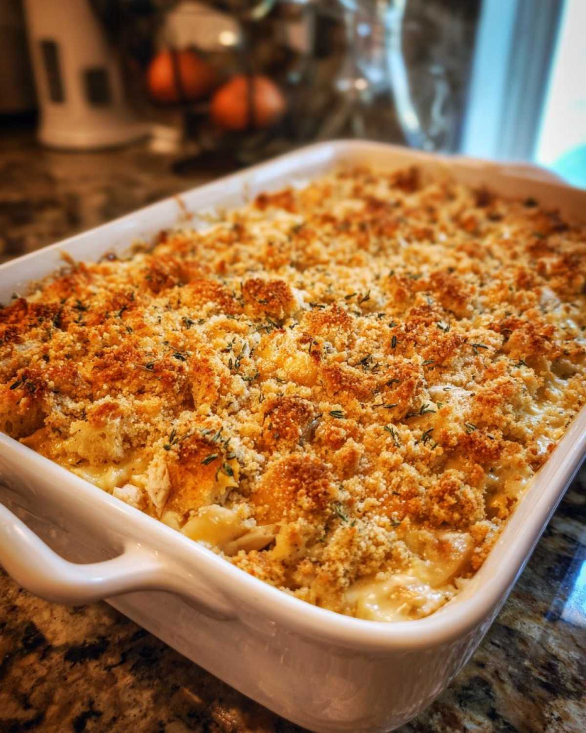 Close-up of a freshly baked chicken stuffing casserole in a white baking dish, with a golden brown crunchy topping.