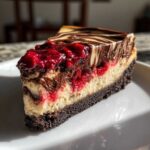 A decadent slice of Cranberry Fudge Cheesecake with a chocolate crust, creamy filling, tart cranberries, and fudge swirls.