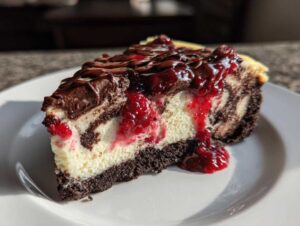 A slice of rich cranberry fudge cheesecake with a chocolate crust, marbled fudge swirls, and a tart cranberry topping.