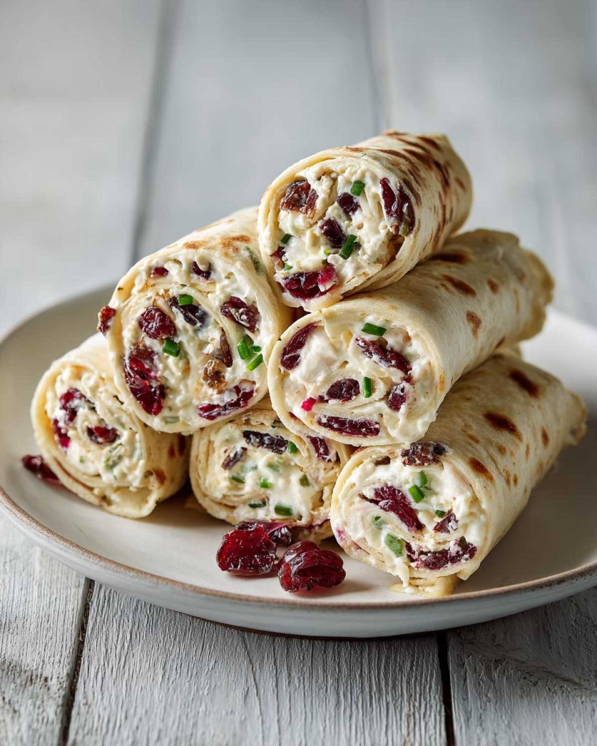 A stack of delicious cranberry roll ups filled with cream cheese, cranberries, and chives.