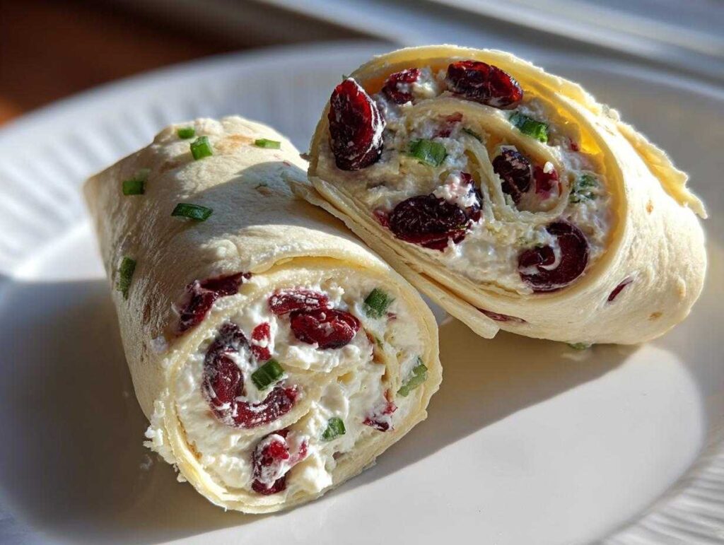 Close-up of two halves of a cranberry roll up, showing the creamy filling with dried cranberries and green onions.