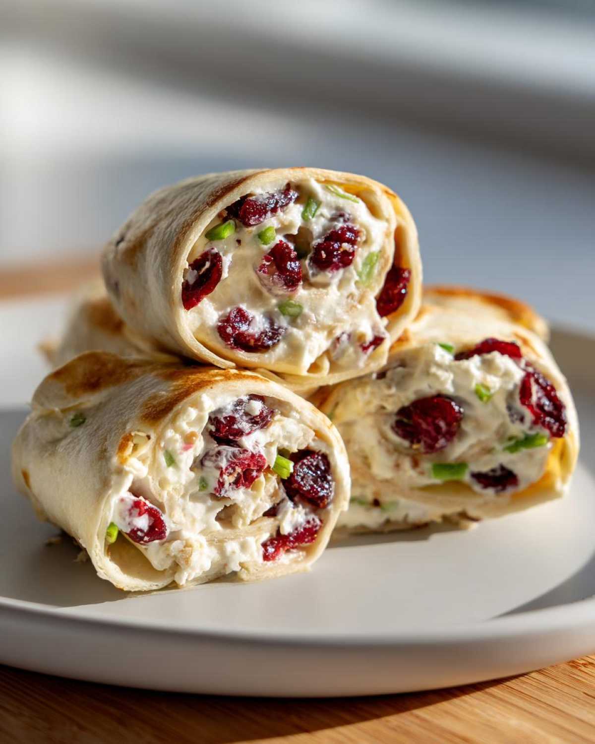 Close-up of several cranberry roll ups filled with a creamy mixture and dried cranberries.