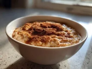 Close-up of a bowl of creamy banana oatmeal generously topped with ground cinnamon.