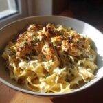 A bowl of creamy garlic parmesan chicken pasta topped with fresh parsley.