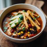 A delicious bowl of crockpot chicken tortilla soup topped with avocado, tortilla strips, and cilantro.