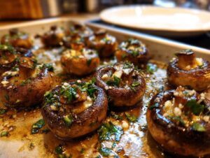 Close-up of roasted garlic butter mushrooms on a baking sheet, glistening with butter and herbs.