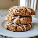 Three delicious coffee cake cookies stacked on a white plate, drizzled with white icing.