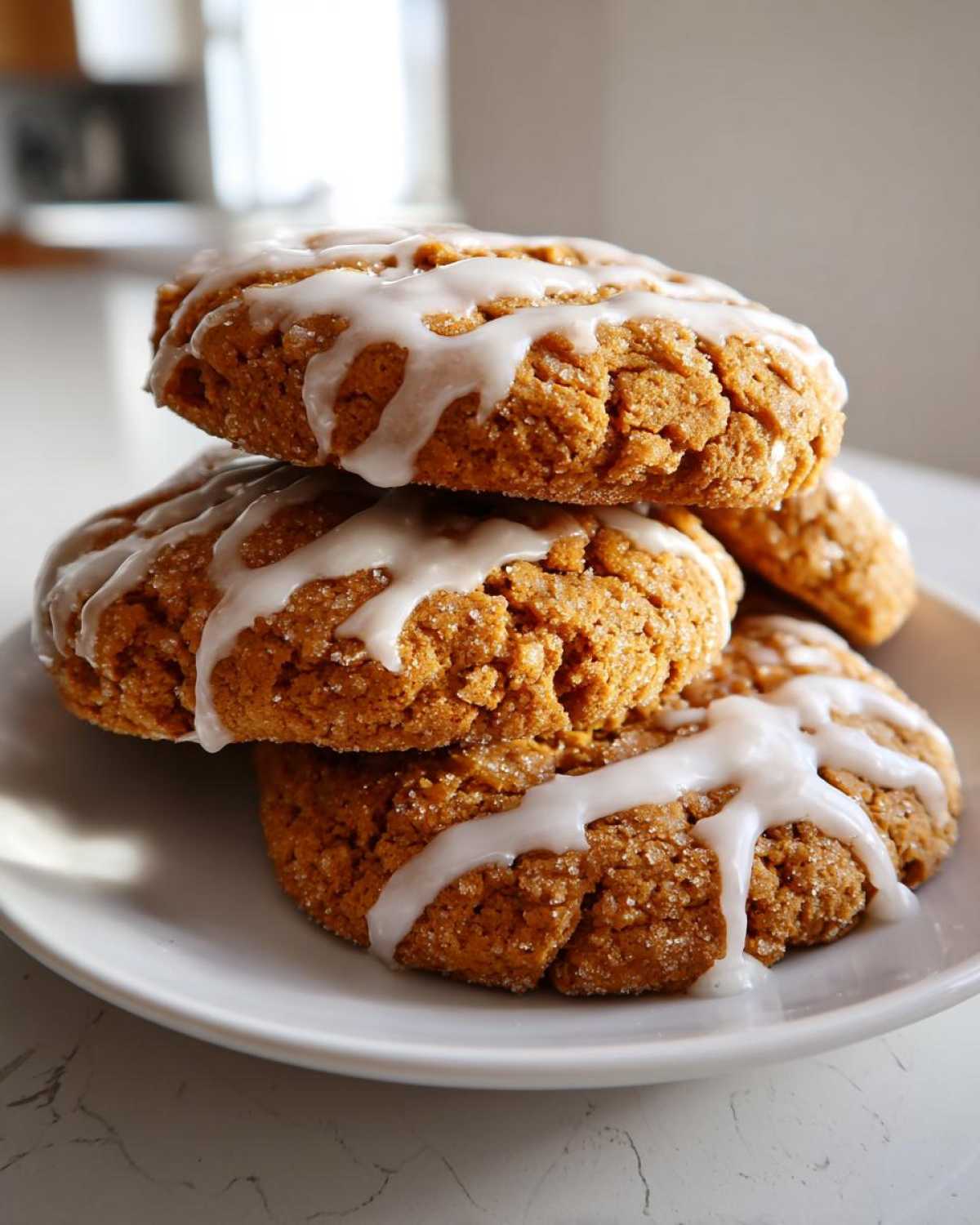 A stack of three thick, crinkled coffee cake cookies topped with white icing drizzle and sugar.
