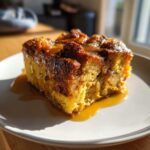 A delicious slice of gluten-free pumpkin bread pudding topped with caramel sauce on a white plate.