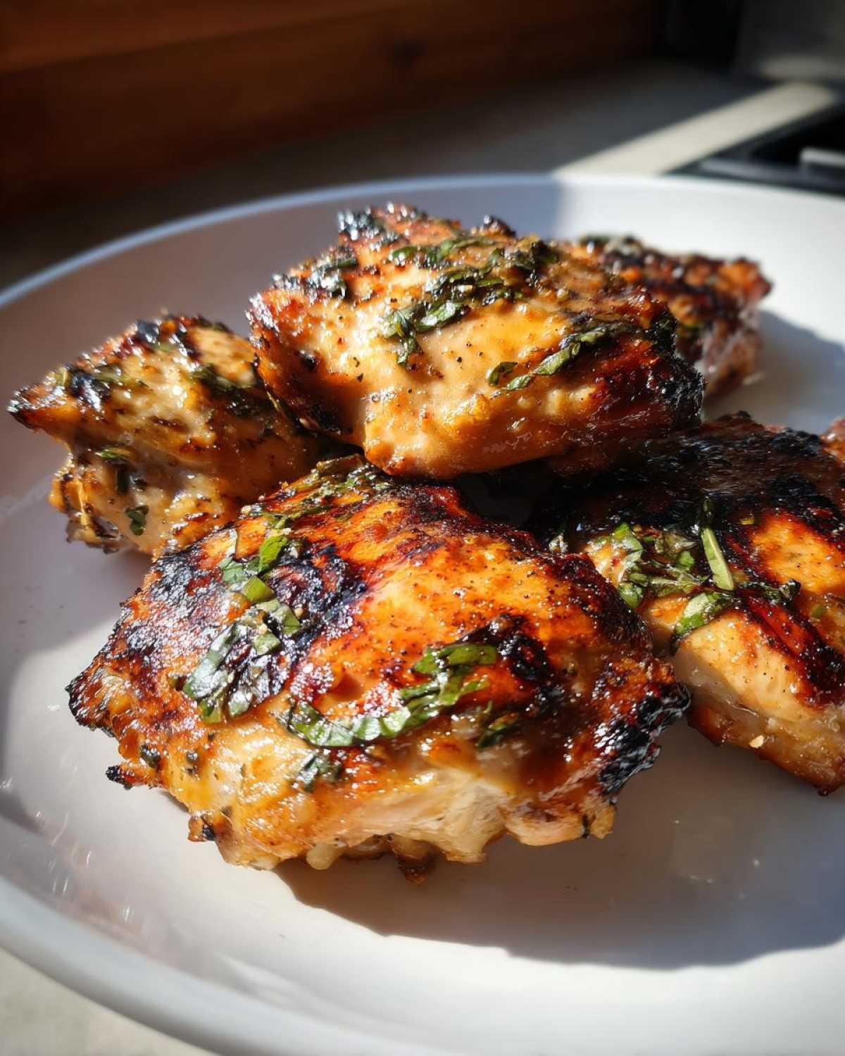 Close-up of perfectly grilled coconut basil chicken pieces, glistening and seasoned with fresh herbs.