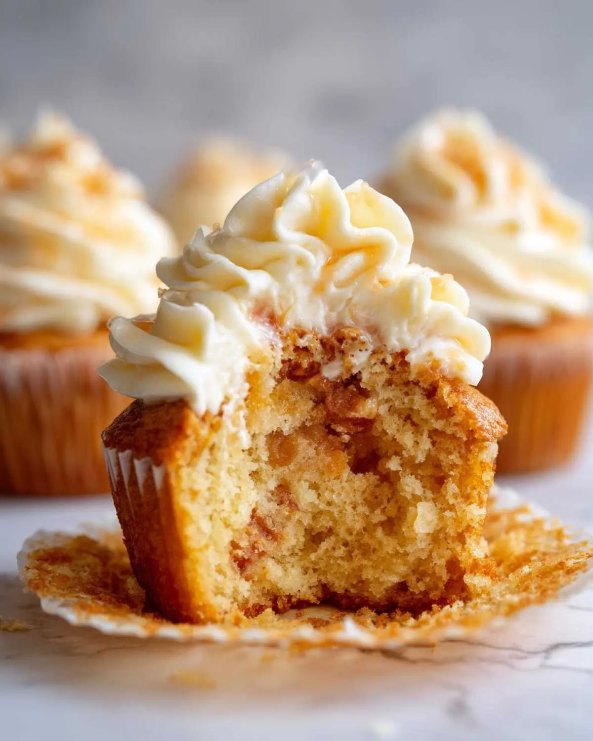 A bite taken out of a Honey Peach Cream Cheese Cupcake, showing the moist crumb and peach filling.