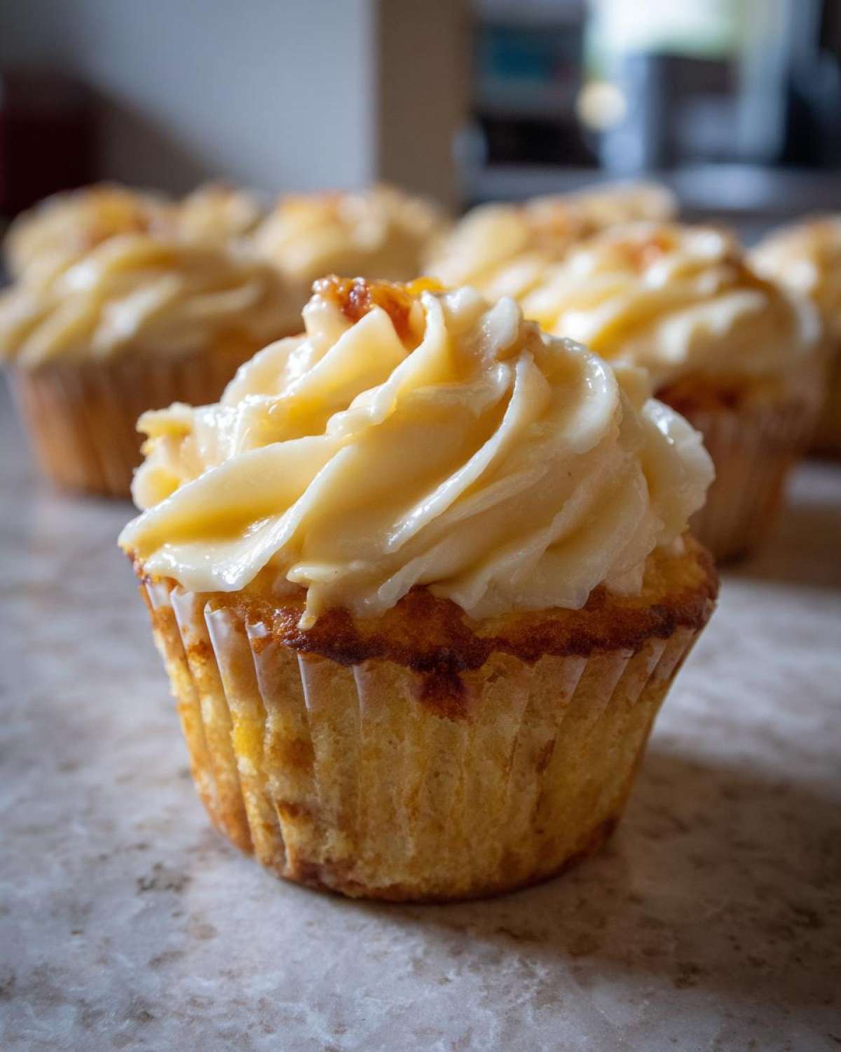 Close-up of a delicious Honey Peach Cream Cheese Cupcake, showcasing its swirled frosting and golden cake.