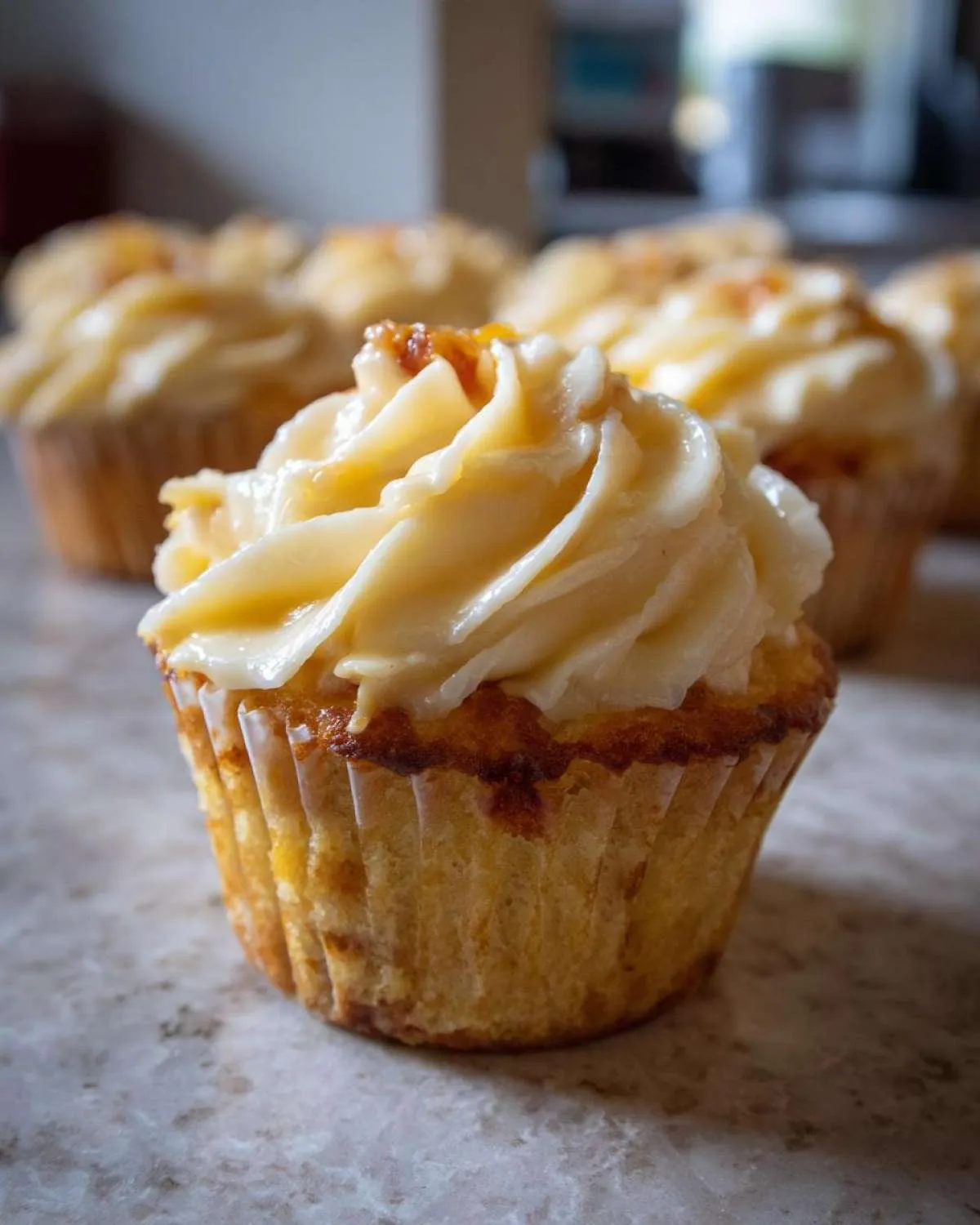 Close-up of a delicious Honey Peach Cream Cheese Cupcake, showcasing its swirled frosting and golden cake.