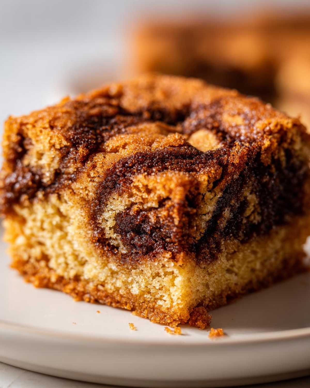 Macro shot of a single square of marbled snickerdoodle blondies showing a rich cinnamon swirl texture.