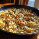 Close-up of a skillet filled with one-pan chicken and buttered noodles, garnished with parsley.