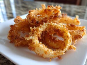 Close-up of a stack of golden-brown, crispy parmesan onion crisps on a white plate.